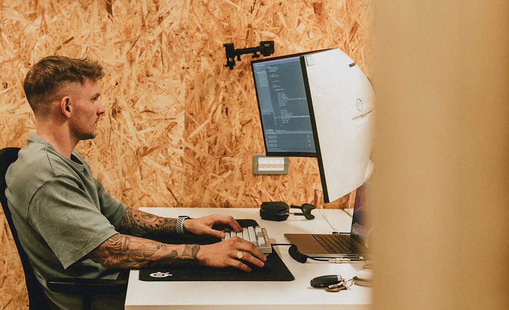 Paolo coding at a dual-monitor desk setup in his workshop