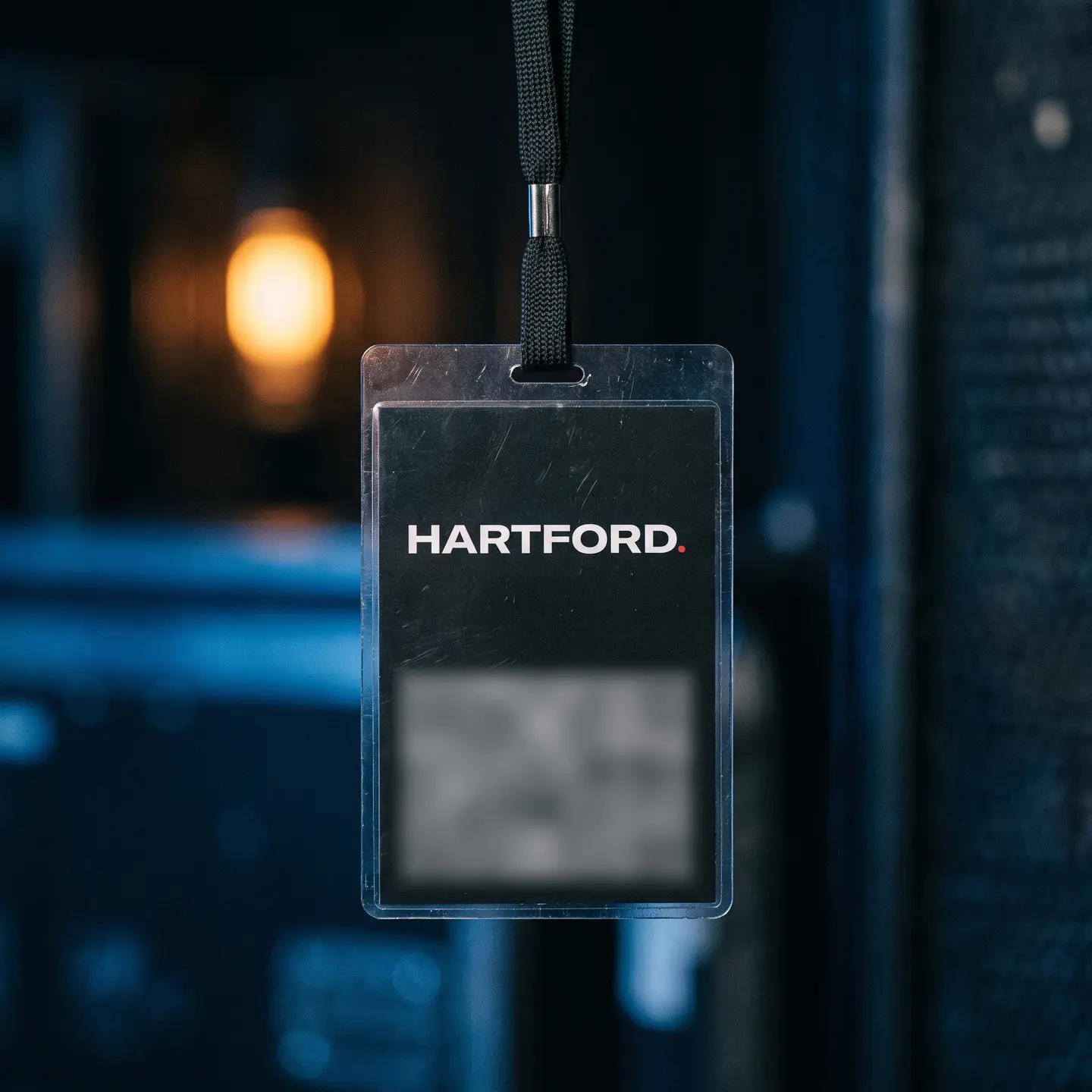 An event crew credential on a black lanyard, carrying the Hartford wordmark at the top of a matte black card.
